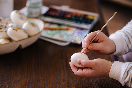 女人在复活节彩蛋节的幻想鸡蛋上画水彩。