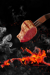 黑色背景中燃烧的木炭上用叉子烹饪的小牛肉片