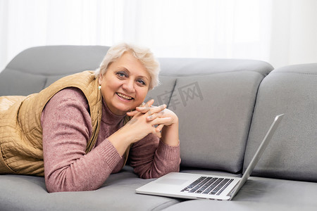 严肃的成熟老年女性在家或在办公室使用笔记本电脑观看培训网络研讨会。 