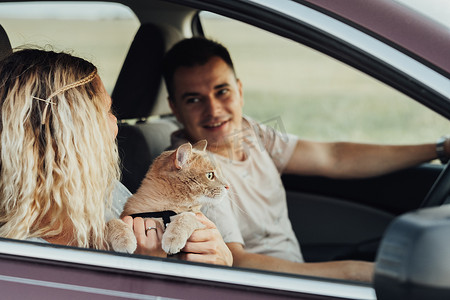 幸福的夫妇带着红猫享受公路旅行，年轻男女带着宠物开车旅行