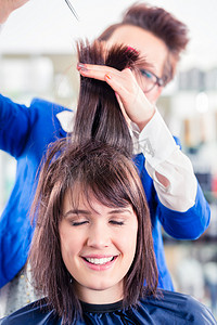 剪头发摄影照片_理发师在店里给女人剪头发