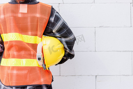 工程师、建筑师、主管工人的后视图穿反光服，以确保工作操作安全并佩戴安全帽