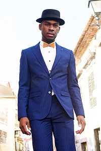 穿着西装和领结站在城市街道上的酷非洲裔美国男模特