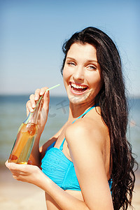 喝饮料的女孩摄影照片_海滩上拿着一瓶饮料的女孩