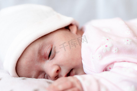 睡觉觉摄影照片_童年、护理、母性、健康概念 — 特写镜头，戴着粉色帽子的小平安平静的新生女婴睡觉休息，躺在柔软温暖的毯子枕窝上，闭上眼睛，睡个小觉