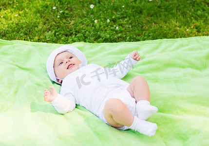 婴儿毛毯摄影照片_微笑的婴儿躺在地板上抬头看