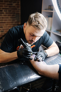 纹身师正在给一个男人的手纹身。