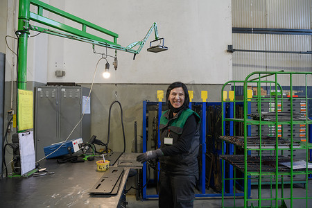 数控专业摄影照片_一位在现代金属生产和加工行业工作的女性焊接产品并为数控机床做好准备