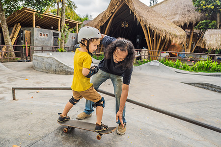 滑板男孩摄影照片_运动男孩在滑板公园与亚洲教练一起学习滑板。