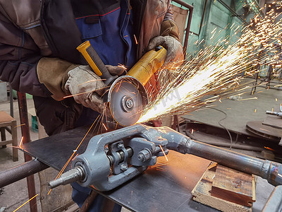 在制造重工业工厂关闭室内，用光滑的钢金属、铁、火花设备进行磨削工作。