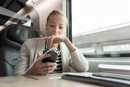 乘火车旅行时用手机通信的女商人。