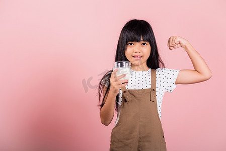 亚洲小孩 10 岁微笑着拿着牛奶杯，展示力量强烈的手势