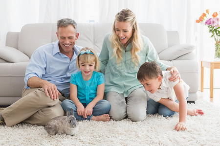 微笑的家庭和他们的兔子在地毯上