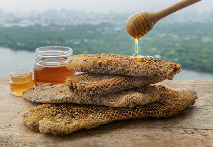 美味的蜂蜜从木制蜂蜜北斗滴下，粘在新鲜的蜂窝上。