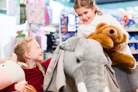 大象大全摄影照片_两个带着毛绒大象的孩子在玩具店玩耍