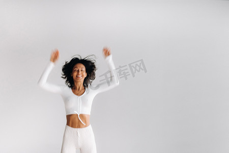 一名身穿白色运动服的女性的模糊剪影在白色背景上跳跃。