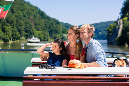 家庭在河上巡游，从船甲板上看山