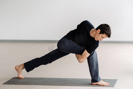 一名身穿黑色T恤的男子站起来训练，在健身房里做伸展运动