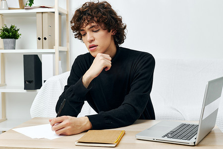 穿着黑色毛衣坐在桌边的卷发家伙课程生活方式技术