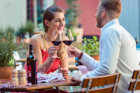 成功男人喝红酒摄影照片_年轻夫妇在餐厅喝红酒