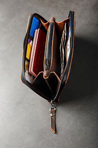 棕色的钱包摄影照片_装有棕色真皮文件的钱包，深色背景手工制作