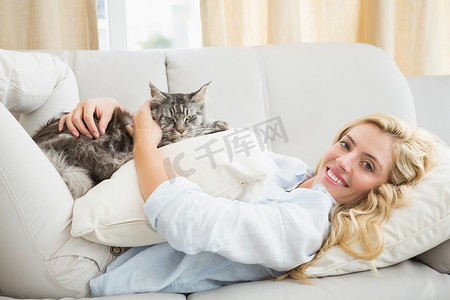 快乐的金发女郎，沙发上有宠物猫