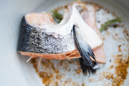 盘子里放着一块切碎的鲑鱼排，还有香料和迷迭香。