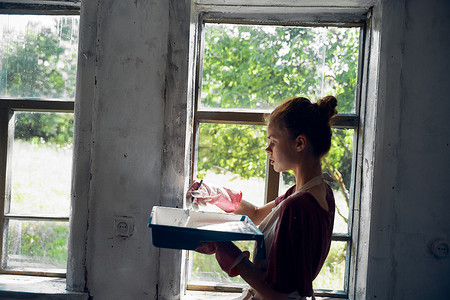 女人在房屋室内装修中油漆窗户