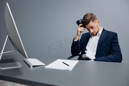 坐在电脑前办公桌前的商人灰色背景