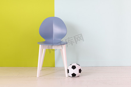 蓝绿色背景前的现代蓝色椅子和足球