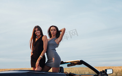 道名摄影照片_路边道路上坐着一辆黑色汽车的两名妇女