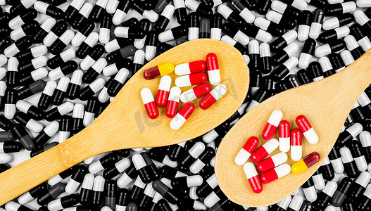 五颜六色的抗生素胶囊药片在木勺子在胶囊黑白背景。