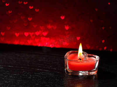 红心散景上的红色燃烧心形蜡烛