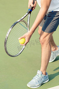 荧光摄影照片_拿着球和网球拍的职业球员的低部分