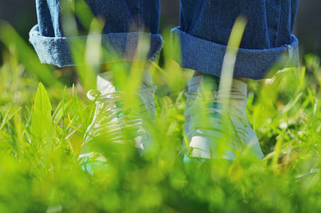 一个年轻的女孩穿着运动鞋站在绿色的草地上。