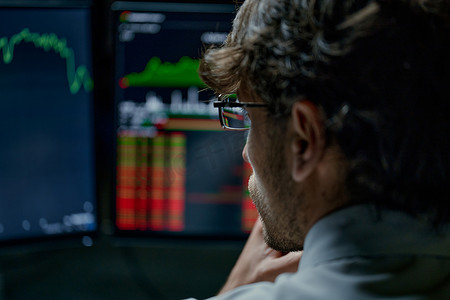 深思熟虑的投资者正在查看带有股市数据的监视器。