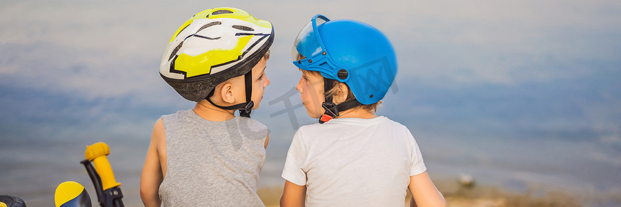 两个男孩骑自行车和踏板车后坐在湖岸上横幅，长格式