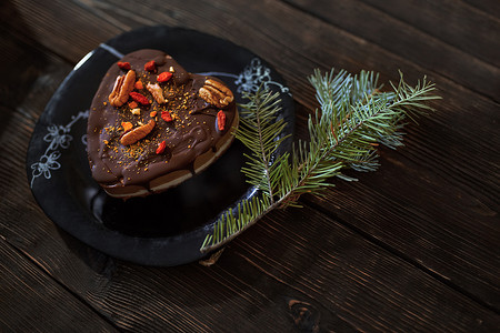 木桌上有圣诞树树枝的无麸质和乳制品巧克力蛋糕