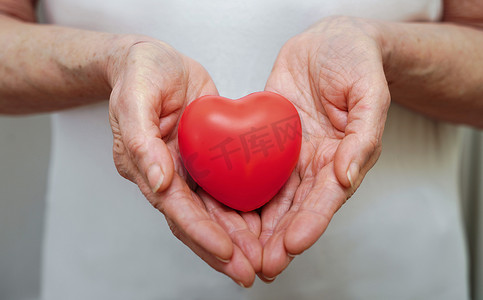 世界卫生日摄影照片_祖母妇女手握红心、医疗保健、爱、器官捐赠、正念、福祉、家庭保险和企业社会责任概念、世界心脏日、世界卫生日、国家器官捐赠日