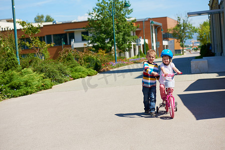 男孩和女孩在公园学习骑自行车