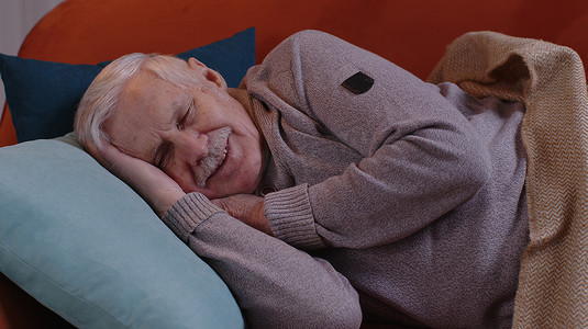 老人微笑的爷爷静静地躺在家里的床上睡觉，健康安宁地睡着