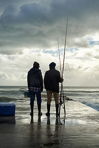这是美好的一天......两个年轻人清晨在海边钓鱼的全长镜头。
