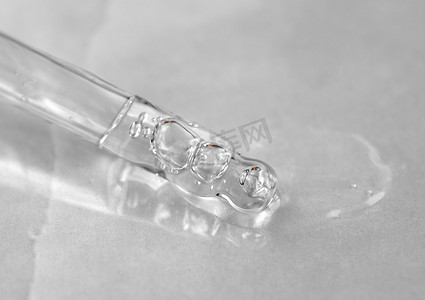 液体流体摄影照片_在单色灰色背景上用液体透明质酸移液器。