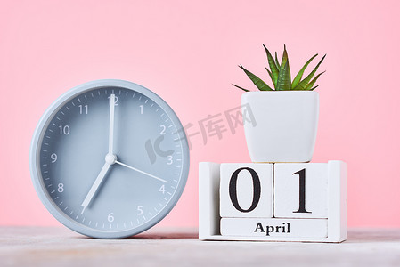 粉红色背景中日期为 4 月 1 日、闹钟和植物的木块日历