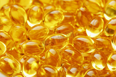 健康胶囊摄影照片_维生素 Omega 3 鱼油金色胶囊特写