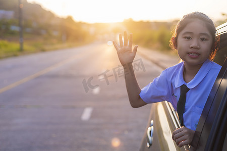 上学的路上，小女孩从车窗里伸出了手，笑着说。