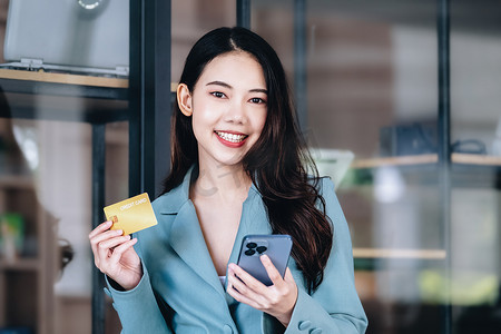 网上购物和网络支付，美丽的亚洲女性正在使用信用卡和手机在数字世界中网上购物或办事。