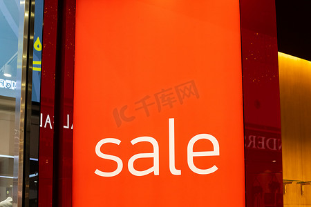 销售商业海报摄影照片_服装店门口的销售标志，大红板，白字。