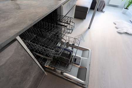 内置wifi摄影照片_现代厨房配有空的内置洗碗机（开门）、不锈钢台下式厨房水槽和自来水、黑色电磁炉、白色台面上安装的炊具。