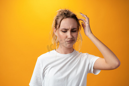 年轻漂亮的女人在黄色背景下思考着向侧面看